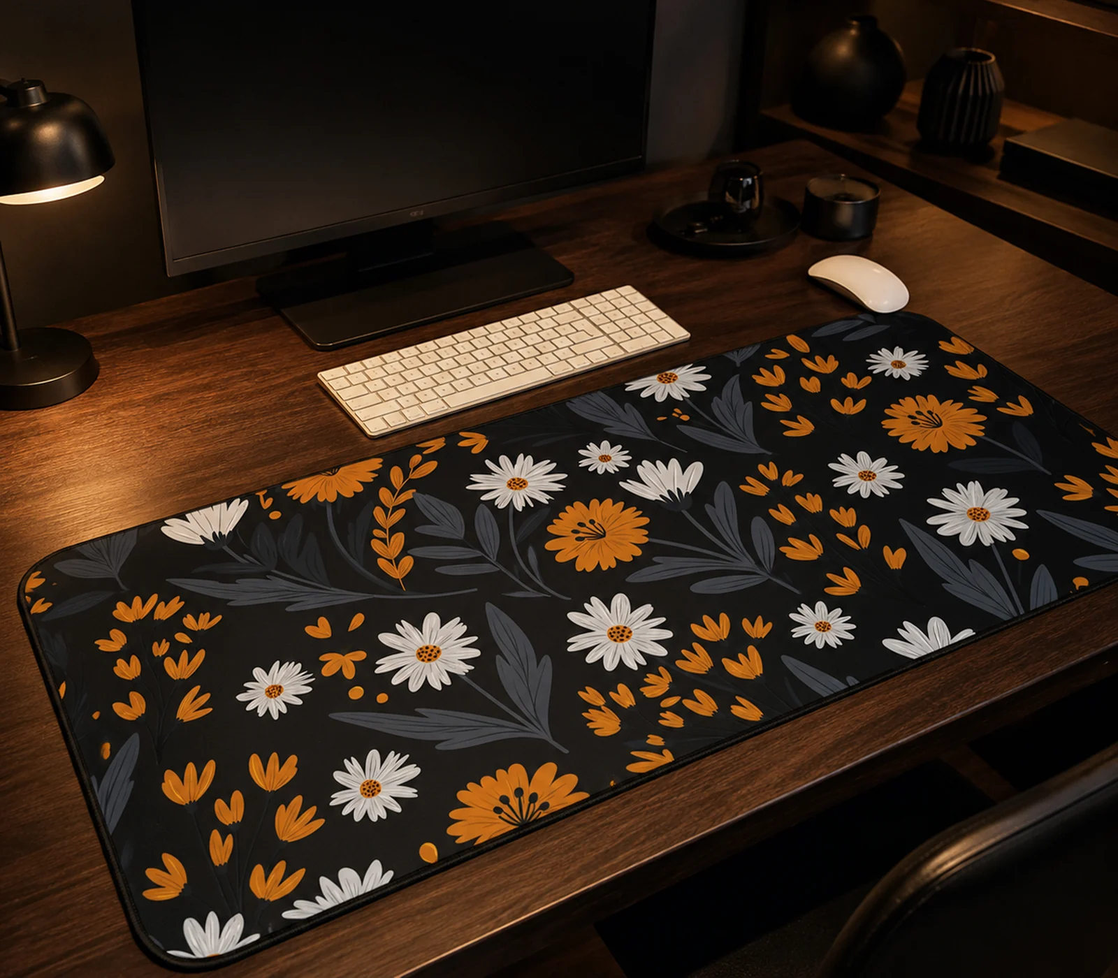 Floral desk mat with orange and white daisies on black - shown on a dark walnut desk under warm lamplight